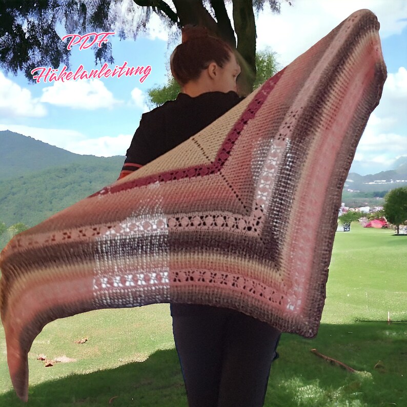 May include: A person wearing a pink, brown and white crocheted shawl with a lacy border. The shawl is draped over the person's shoulders and back. The text "PDF H&auml;kelanleitung" is visible in the top left corner of the image.