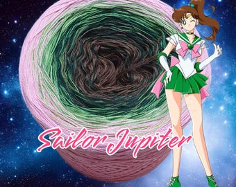 May include: A ball of yarn with pink, green, and brown stripes against a starry background. The text "Sailor Jupiter" is written in pink letters below the yarn ball. A cartoon character with brown hair and a green dress is standing to the right of the yarn ball.