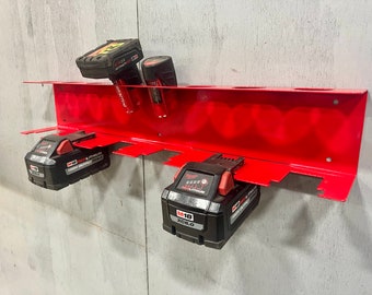May include: Red metal wall-mounted battery storage rack with six slots. Two black and red Milwaukee M18 XC6.0 batteries are in the rack. The rack is mounted on a gray concrete wall.