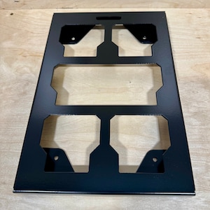 May include: Black metal wall mount with six cutouts for organizing items. The mount has a rectangular shape and is designed for hanging on a wall.