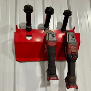 May include: Three red and black power tools hang on a red metal wall mount. The tools have black handles and are labeled "FUEL".