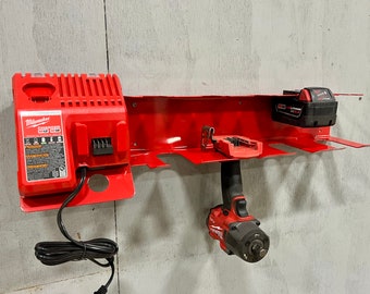 May include: Red metal wall-mounted storage rack with a red and black Milwaukee charger, a black battery, and a red and black impact wrench.