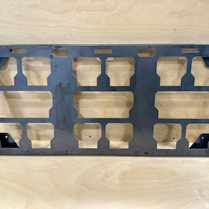 May include: A metal rack with 16 rectangular cutouts, designed for organizing and storing items. The rack has a dark gray finish and is made of sturdy metal.