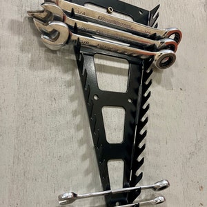 May include: A black metal wrench organizer with several wrenches. The wrenches are silver and have the brand name "GEARWRENCH" printed on them. The organizer is mounted on a light gray surface.