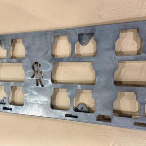 May include: A metal plate with a grid of cutouts, designed for mounting items. The plate has a logo in the centre that reads "SCR".