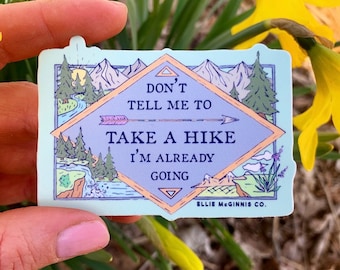 Puede incluir: Una pegatina azul y naranja con una escena de montaña y el texto "No me digas que vaya de excursión, ya estoy en camino" y el nombre de la empresa "Ellie McGinnis Co."