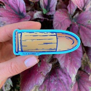 May include: A blue and brown bullet sticker with the text "Ellie McGinnis Co."