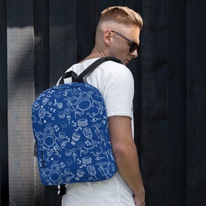 May include: A blue backpack with a white pattern of musical instruments, including drums, microphones, and music notes.