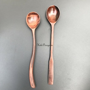 May include: Two wooden spoons, one with a curved handle and one with a straight handle. The spoons are both brown and have a natural wood finish. The spoons are labelled with the numbers 6 and 7.