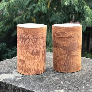 Könnte beinhalten: Zwei Holzbehälter mit einer hellbraunen Oberfläche und einer weißen Oberseite. Die Behälter stehen auf einer grauen Betonfläche.