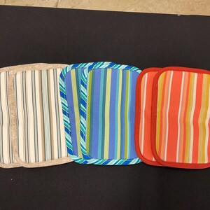 May include: Three rectangular fabric pot holders with striped patterns. The pot holders feature beige, blue, and red borders. The striped patterns include beige, brown, blue, green, yellow, and orange.