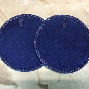 May include: Two round blue pot holders with a white, pink, and blue patterned trim.