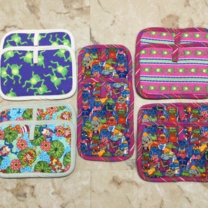 May include: Set of eight colorful pot holders with various frog designs. The pot holders are made of fabric and have a white trim. Some of the designs include frogs wearing hats, frogs with flowers, and frogs with stripes.