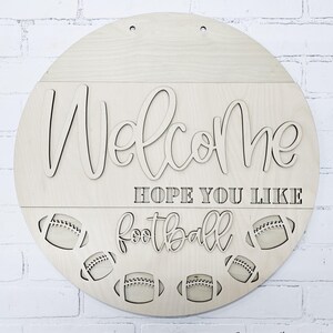 以下が含まれることがあります： 「Welcome Hope You Like Football」という文字と、下部にフットボールのデザインが施された木製ウェルカムサインです。