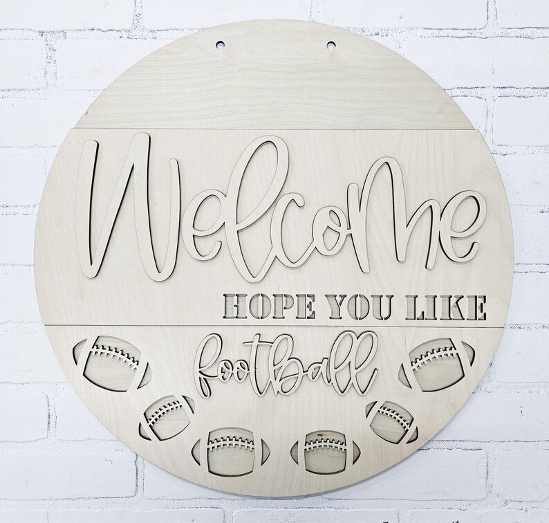 以下が含まれることがあります： 「Welcome Hope You Like Football」という文字と、下部にフットボールのデザインが施された木製ウェルカムサインです。