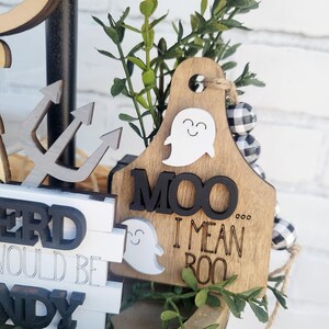 May include: A tiered wooden tray decorated with a ghost, a wooden sign that says "MOO I MEAN BOO", and black and white buffalo check ribbon.