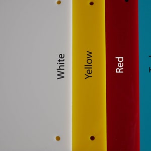 May include: A collection of colorful rectangular acrylic sheets in white, yellow, red, teal, and orange. Each sheet has a hole in the top corners and the color name printed vertically. The sheets are arranged side by side.