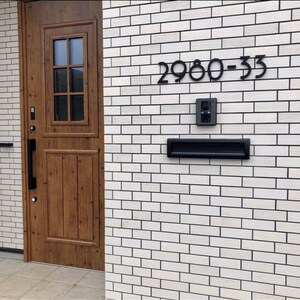 May include: A white brick building with a wooden door and a black mailbox. The house number is 2980-33.