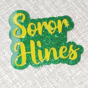 May include: Green glitter background with the name "Soren Hines" written in yellow glitter.