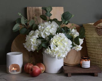 Arreglo floral artificial de hortensias blancas y eucalipto verde hecho a mano: ramo de invierno de flores artificiales en jarrón de cristal.