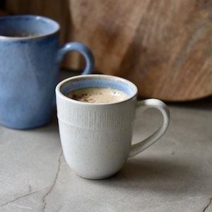 Taza de cerámica esmaltada artesanal en blanco lechoso y azul, de gres, en relieve, ideal como regalo de cumpleaños o para mamá.