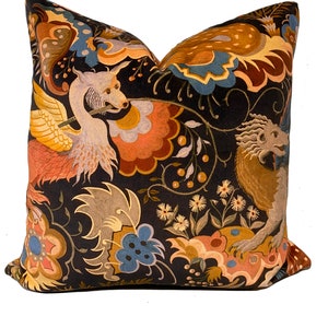 May include: A black velvet pillow with a colorful floral pattern featuring mythical creatures. The pattern includes a winged creature with a long beak and a dragon-like creature with a long tail. The pillow is decorated with a variety of flowers, leaves, and vines.