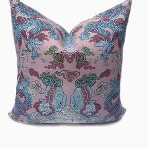 May include: Pink pillow with a blue and red dragon pattern. The pillow is decorated with a repeating pattern of dragons, clouds, and other Chinese symbols.
