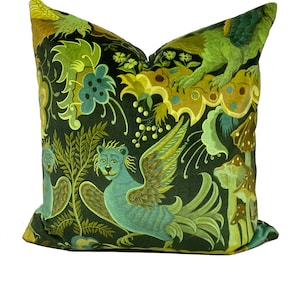 May include: A green velvet cushion with a whimsical design featuring a blue bird with a lion's head, mushrooms, and floral patterns.
