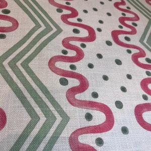 May include: White fabric with a repeating pattern of green zigzags, pink wavy lines, and dark green dots.