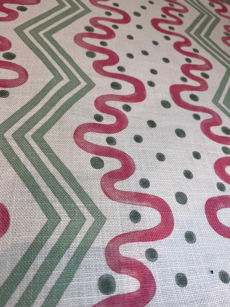 May include: White fabric with a repeating pattern of green zigzags, pink wavy lines, and dark green dots.