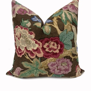 May include: A brown floral pillow with a large floral pattern in shades of pink, red, and green. The pillow is made of a soft, linen-like fabric.