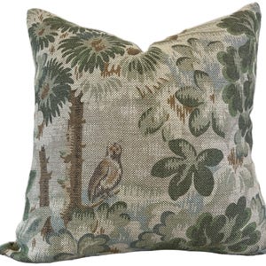 May include: A decorative cushion with a beige background and a green floral pattern. The cushion features a stylised bird design and a textured fabric.