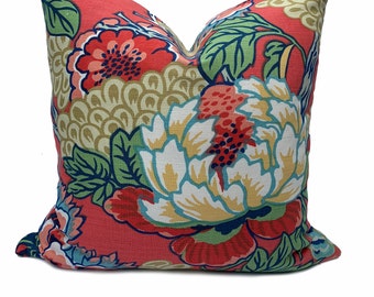 May include: A red pillow with a floral pattern featuring large white, yellow, and red flowers with green leaves. The background is a solid red color.