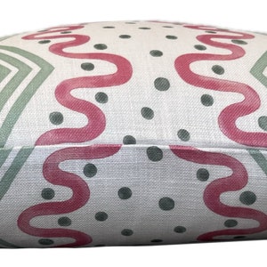 May include: A white pillow with a geometric pattern in shades of pink and green. The pattern features wavy lines and dots.