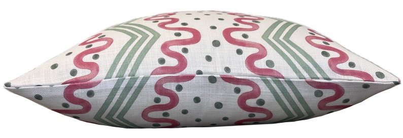 May include: A white pillow with a geometric pattern in shades of pink and green. The pattern features wavy lines and dots.