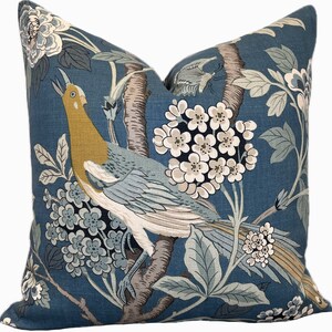 May include: A blue throw pillow with a floral pattern featuring a bird, branches, and white flowers.