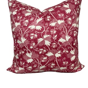 Puede incluir: Una almohada roja y blanca con un diseño floral. La almohada está hecha de una tela suave y texturizada.