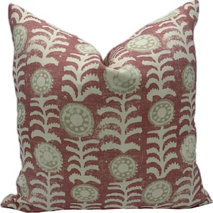 May include: A square decorative pillow with a floral pattern. The pillow features a repeating design of cream-colored flowers and stems against a red background. The pillow is made of a textured fabric and has a soft, inviting appearance.