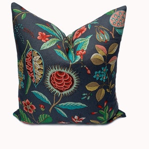 May include: A dark blue cushion with a floral pattern featuring red, pink, yellow, and blue flowers on a dark blue background.
