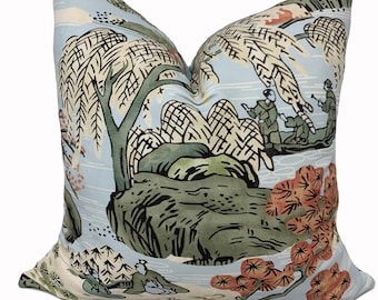 May include: A blue pillow with a Japanese-inspired design featuring a willow tree, mountains, and figures in a boat. The design is in shades of green, brown, and orange.