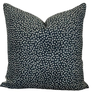 May include: A dark blue throw pillow with a white floral pattern. The pillow is made of a soft, textured fabric.
