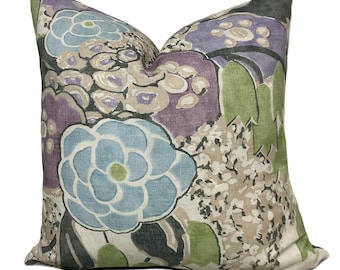 Può includere: Un cuscino decorativo con un motivo floreale in tonalità di viola, blu, verde e beige. Il cuscino presenta grandi fiori e foglie stilizzati.