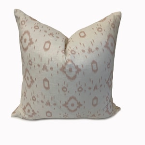 May include: A white throw pillow with a pink geometric pattern. The pillow is made of a soft, textured fabric.