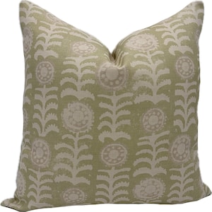 May include: A square decorative pillow with a light green background and a repeating floral pattern in a cream color. The pillow has a soft, textured appearance, suitable for home decor.