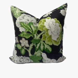 May include: Black pillow with a white and green floral pattern. The pattern features large flowers, leaves, and a small bird.