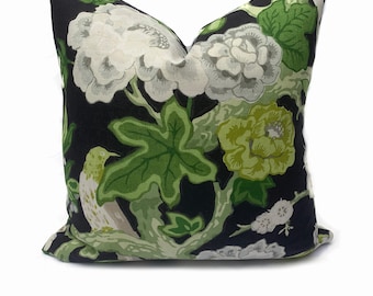 May include: Black pillow with a floral pattern featuring white and green flowers, green leaves, and a white bird on a branch.