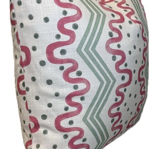 May include: A white pillow with a geometric pattern in shades of pink and green. The pattern features wavy lines, zigzags, and polka dots.