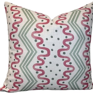 May include: A white pillow with a geometric pattern in shades of pink and green. The pattern features wavy lines and dots.