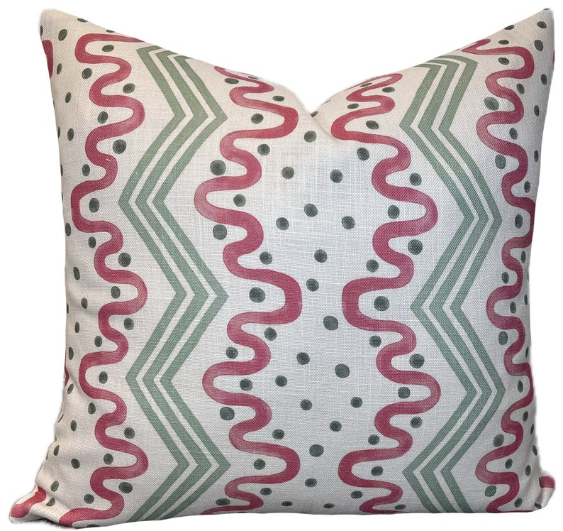 May include: A white pillow with a geometric pattern in shades of pink and green. The pattern features wavy lines and dots.