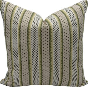 May include: A square decorative pillow with a striped pattern. The design features vertical stripes in beige, olive green, and white. The stripes alternate between dotted and floral patterns, creating a textured look. The pillow is made of a soft fabric.